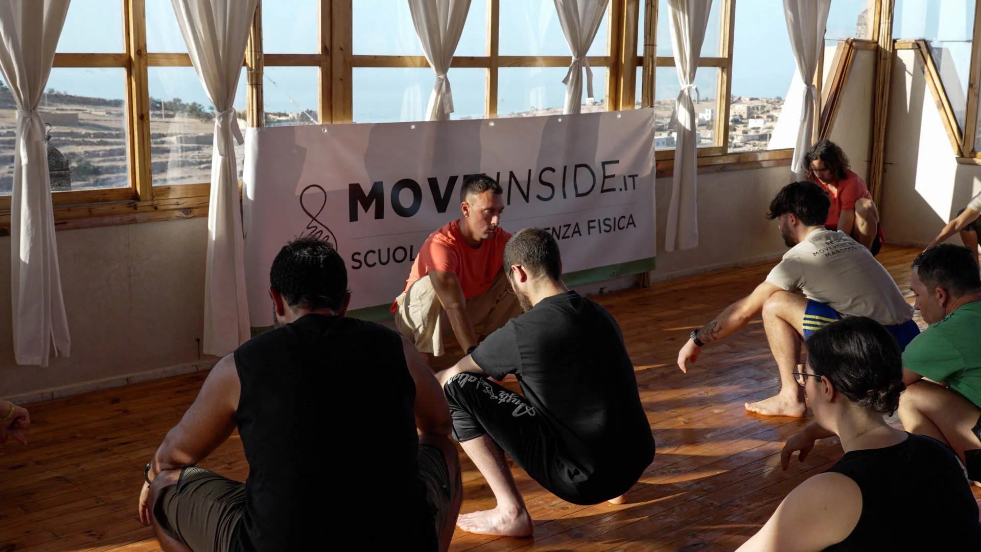 Gruppo seduto a terra in ascolto durante una sessione di lavoro interiore, alternativa in movimento alla meditazione vipassana