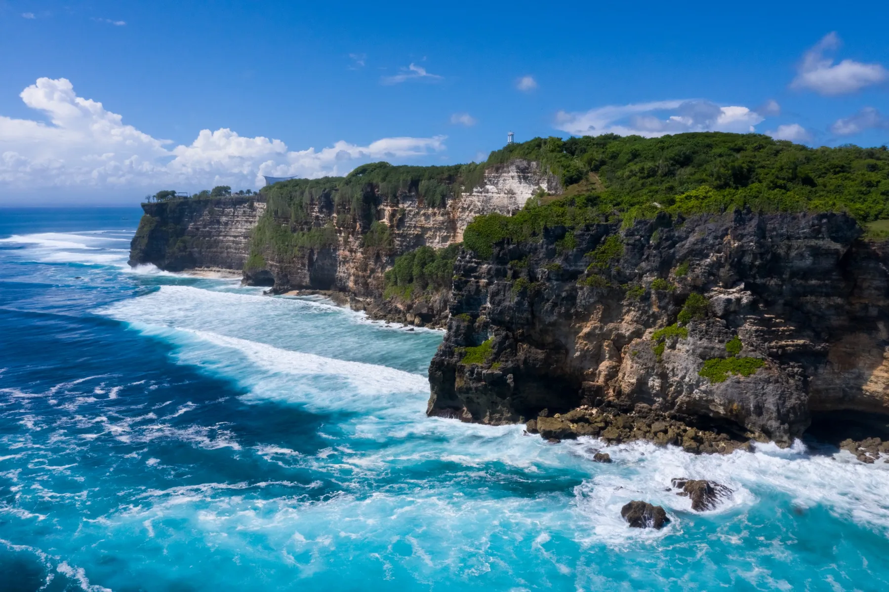 Retreat a Bali: vista aerea delle scogliere di Uluwatu sull'oceano Indiano, con onde turchesi e vegetazione tropicale sulla falesia